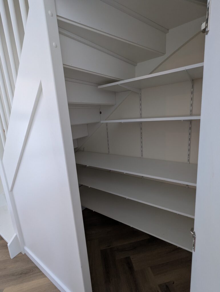 Maatwerk trapkast die een complete kast vormt, ontworpen om een ongebruikte ruimte functioneel te maken, met slimme indeling 