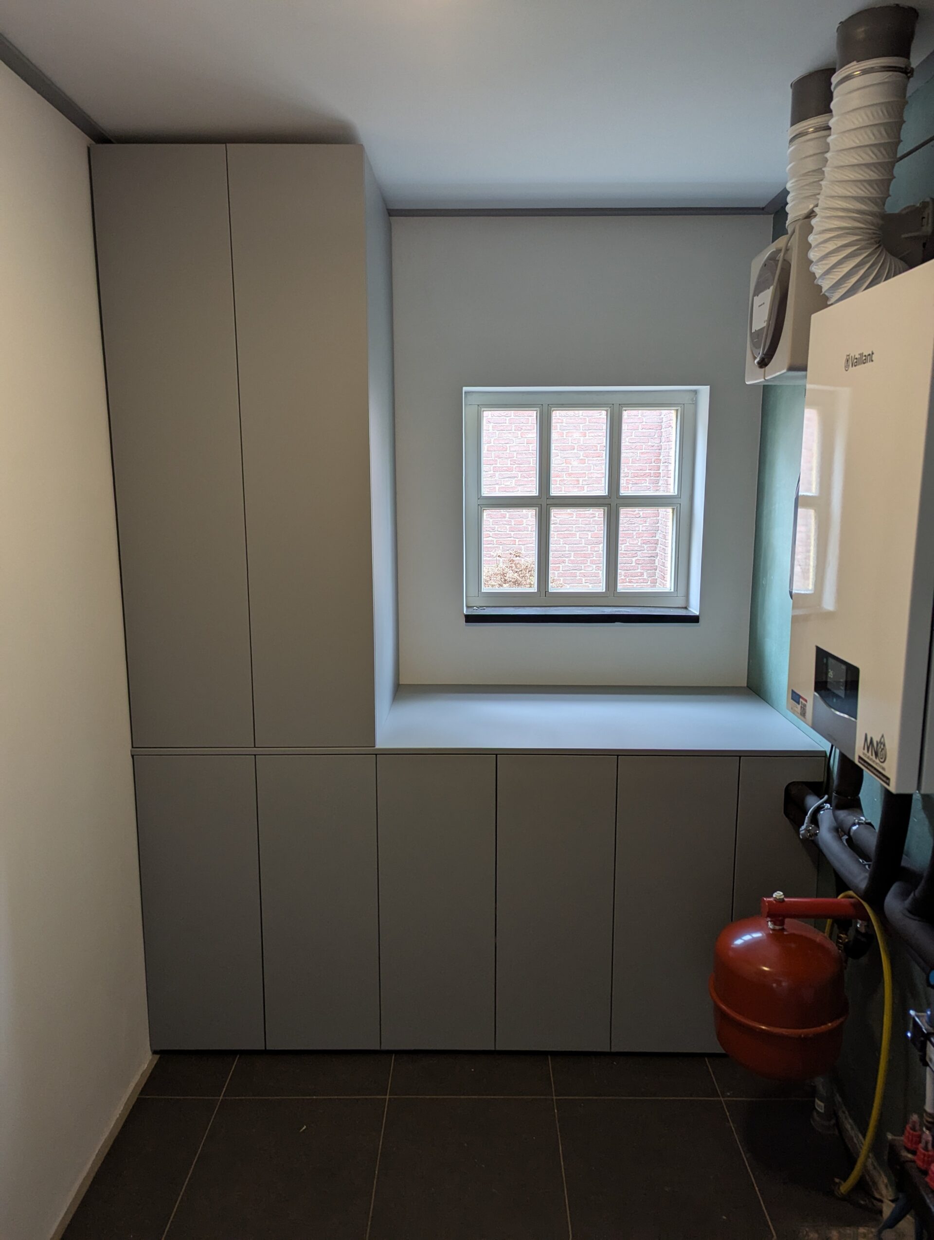 Maatwerk bijkeukenkast met ruimte voor de wasmachine en weggewerkte ketel, ontworpen voor een functioneel en stijlvol interieur op maat.