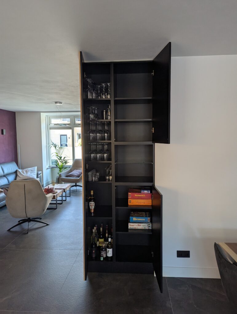 Kasten op maat in de woonkamer, afgewerkt met akoestische panelen en inclusief een wand achter de tv, voorzien van opbergruimte, planken en deuren, ontworpen als functioneel interieur maatwerk dat zowel opslag als geluidsdemping biedt