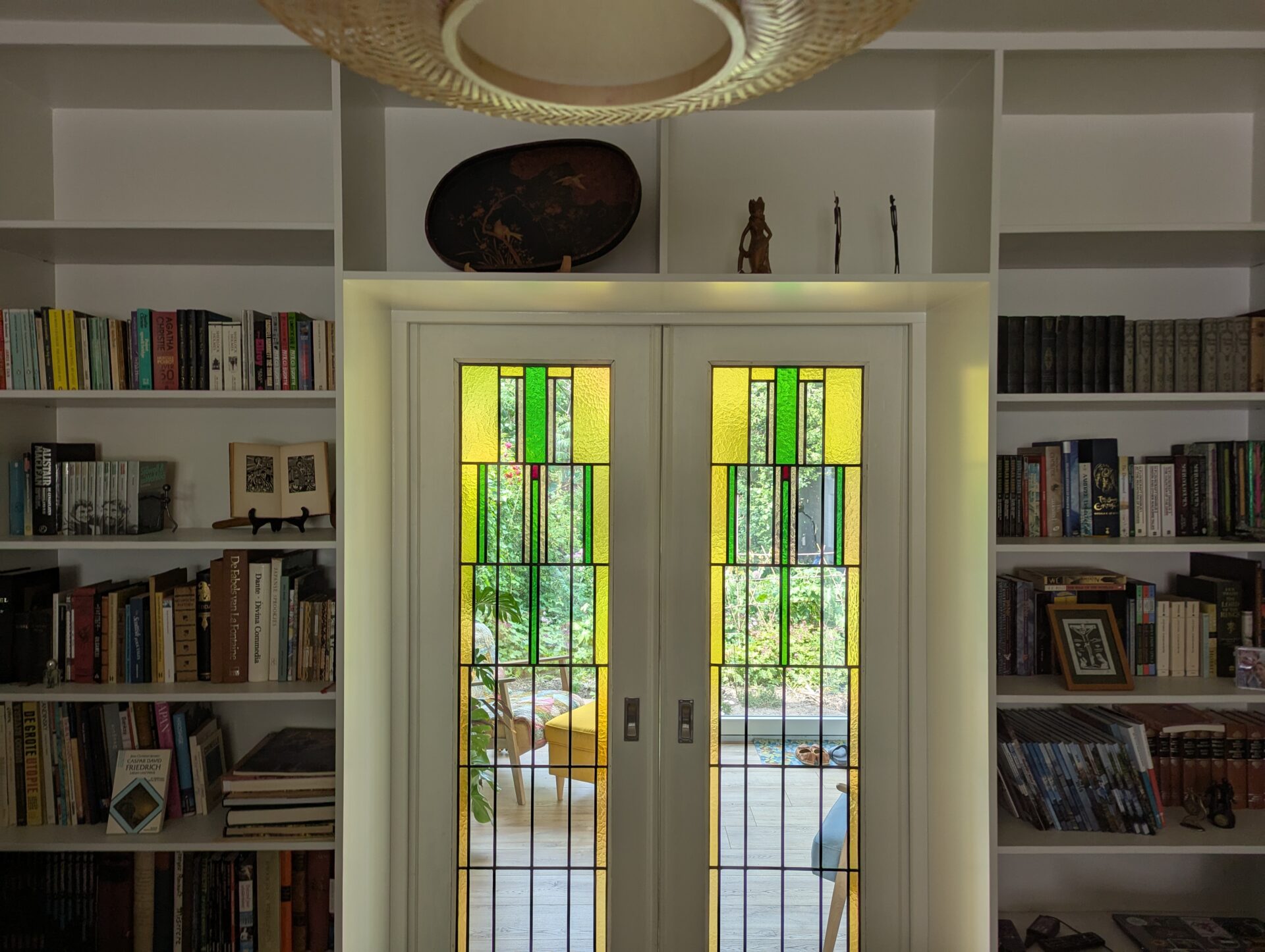 Maatwerk roomdivider met ensuite deuren die tevens functioneren als boekenkast, ontworpen om ruimtes te scheiden terwijl het opbergruimte en stijlvolle presentatie van boeken biedt, modern en functioneel design