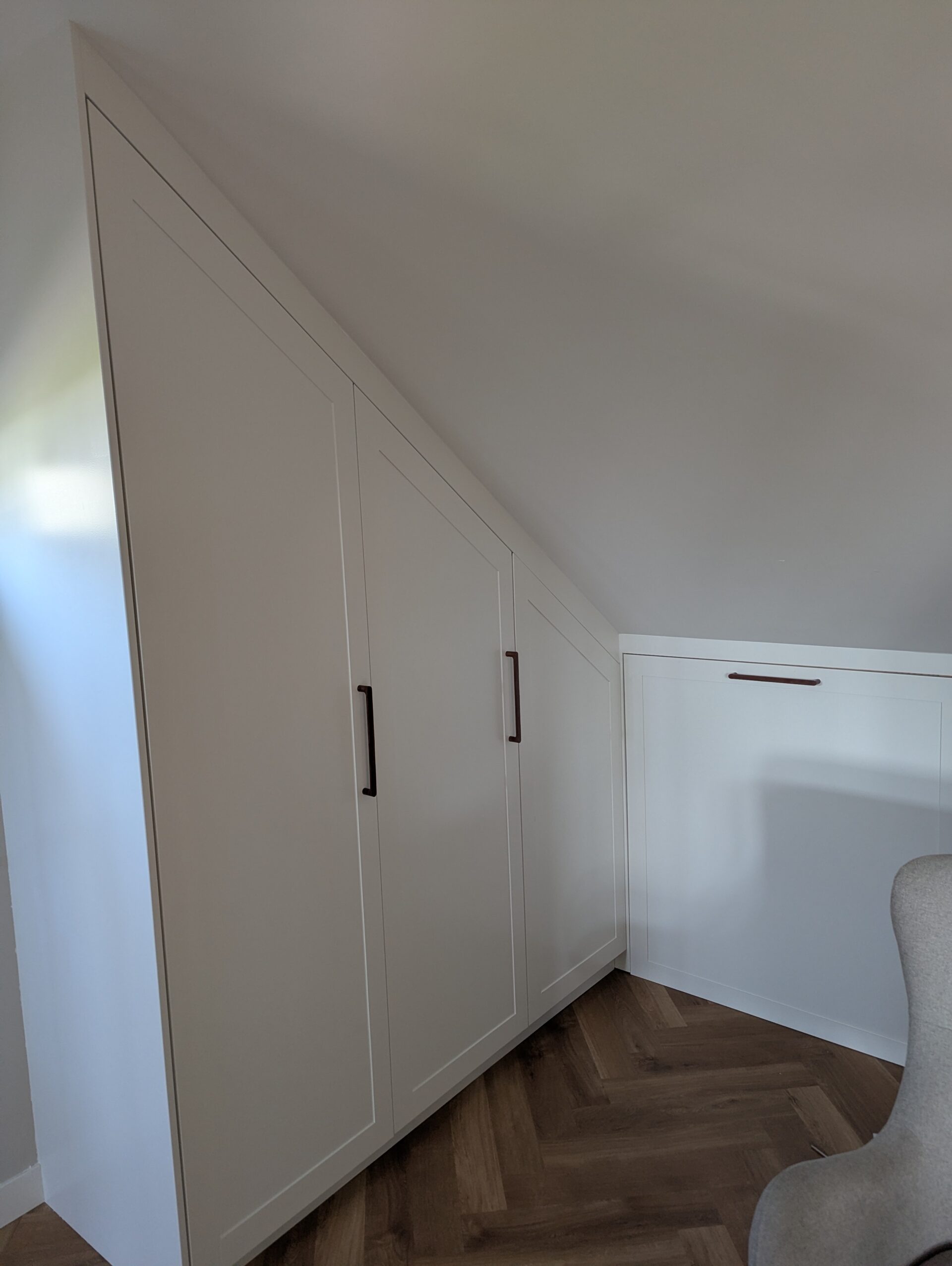 Kast op maat voor schuine wand met opbergruimte en planken.